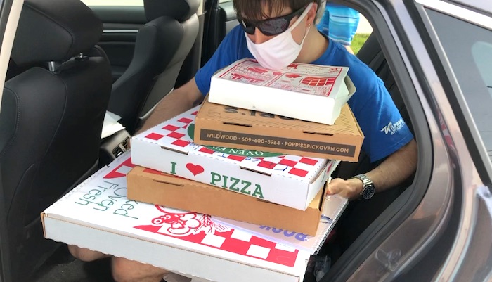 Frank carrying many boxes of pizzas